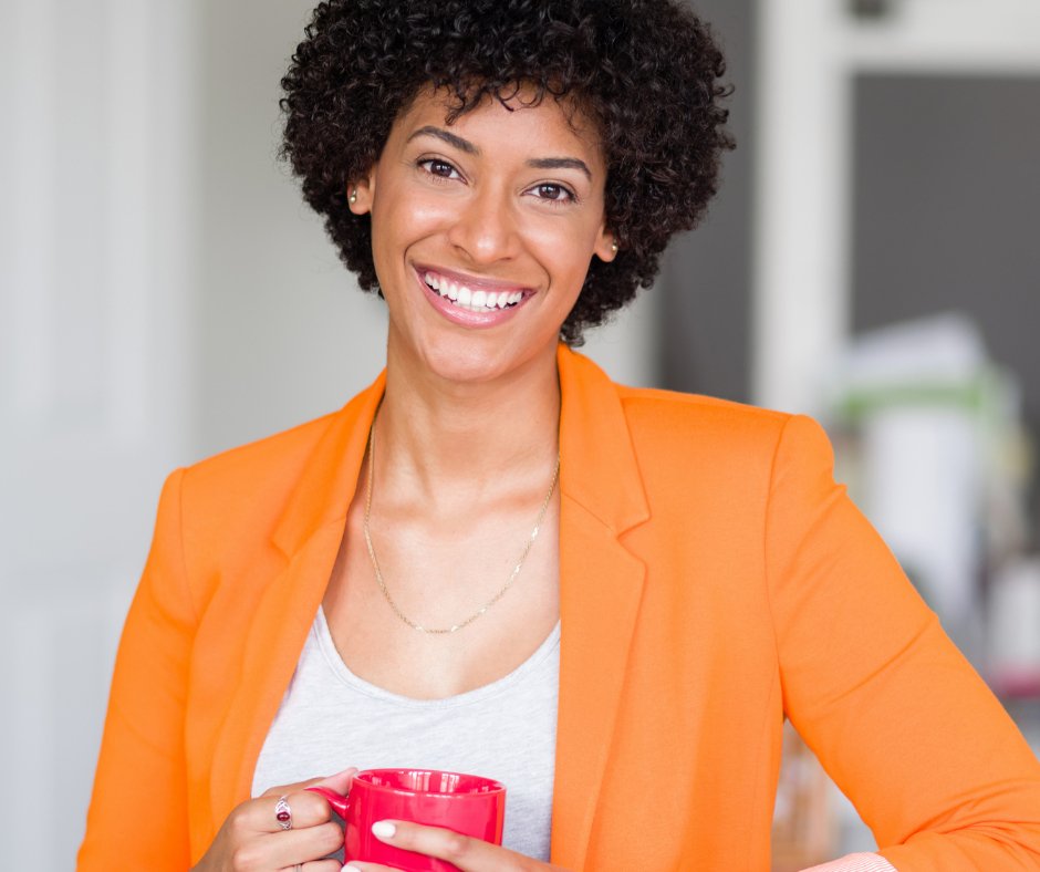 Happy woman in an orange jacket holding a mug